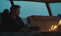 a man sitting by the fire on a couch holding a mug