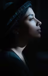 a woman with braids and jewelry looks off into the distance