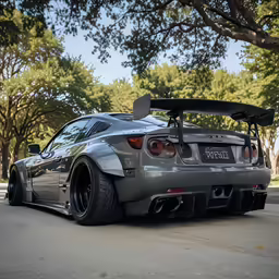 a silver sports car parked next to trees on the side of the road
