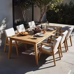 a long table set with white chairs and plates on it