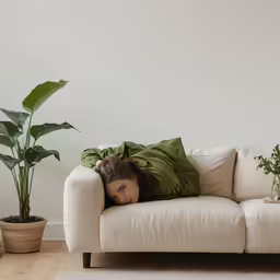 a woman lying on a couch under a green pillow