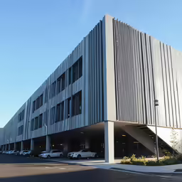 a large modern building with several cars parked on the outside