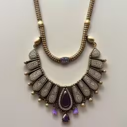 a necklace with lots of purple stones and diamonds,a necklace has many beads and is set with amethysts,a necklace with several pendants that includes gold colored stones and gems,a long necklace with a pendant and stones on top,a necklace with a lot of different jewelry
