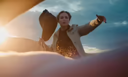 a woman in a tan jacket walking by an airplane