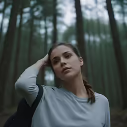 the woman in the grey shirt is in a forest