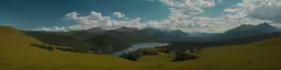 a scenic photo of a green landscape with mountains in the background