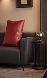 a leather chair with red pillow and a lamp
