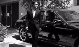 a man wearing a suit standing next to his car