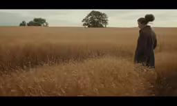 the woman is standing alone in the large field