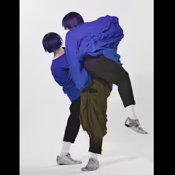 two young people with dark hair and blue shirts on are dancing,two people are in the same direction with a purple shirt