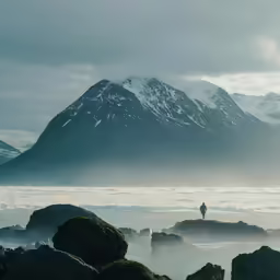 a man standing on top of rocks with mountains in the background