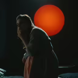 a girl standing next to a bed with a red ball in the background