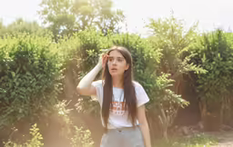 a young woman wearing a shirt and shorts holds her hands to her head