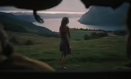 a young woman standing in the grass and looking out