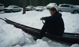 a man sitting in the snow on top of a boat