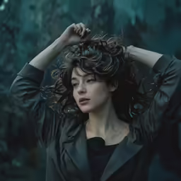 the young woman with the wavy hair has her hands behind her head