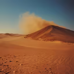 a dune with some sand blowing up in the background