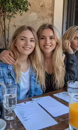 two girls smile for the camera, as they sit together
