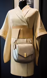 a beige and grey leather belt bag hanging on a dummy head