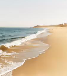 a sandy beach covered in waves next to a cliff