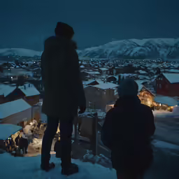 two people looking out over the town covered in snow