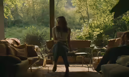 a woman sits in the screened porch on her knees,