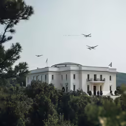 a large white house that has planes flying by