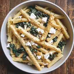pasta with parmesan cheese and greens in a bowl