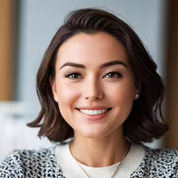 the smiling woman wearing pearls has a large pearl in her left hand