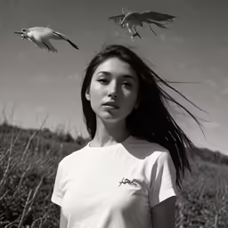 woman standing outside next to plants with birds flying around her