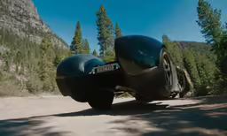 a black motorcycle is going down the road in the woods