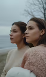 two women stand near the ocean on the beach