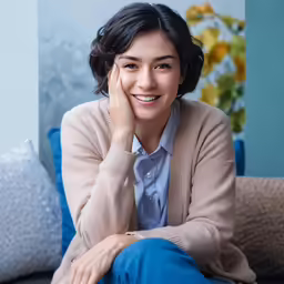 smiling woman with hand on her face sitting