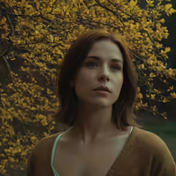 a young woman is standing near a tree