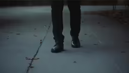 a person wearing some black shoes walking down the street