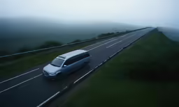 van driving on road near hill during foggy day
