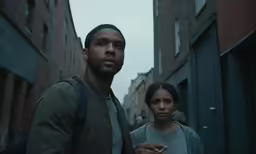 a man and woman walking down a street in the rain