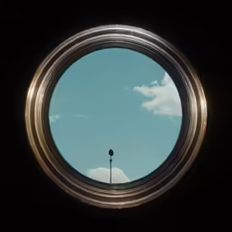 a round window that shows the blue sky with clouds