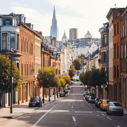 looking down an urban street of tall buildings with the steeples of a cathedral in the distance