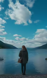 the back end of a person standing at a lake with their hands together