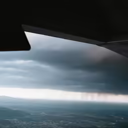 rain coming down over a city below a cloudy sky