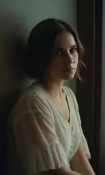 young woman in an elegant white dress looking out the window