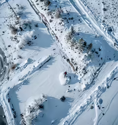 an aerial view of a snowy mountain, trees, and parking lot