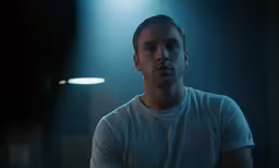 a man in a white shirt looks at the camera
