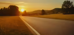 the sun is setting over an empty road