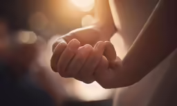 two people are holding hands on the beach