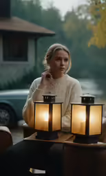a woman sitting next to two lanterns while looking at her phone