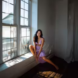 a woman sitting in front of a window with a curtain,a woman posing for the camera next to a window