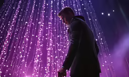 a man holding a microphone in front of a wall of lights