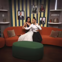 two women pose for a picture while sitting on a couch